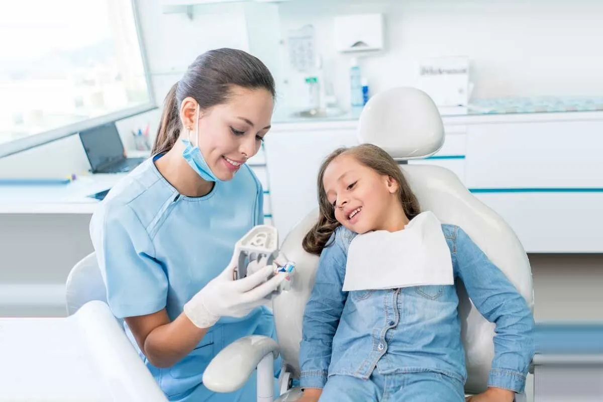 A female dentist speaking with their patient a young girl.
