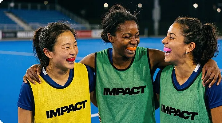 Team of players wearing IMPACT bibs smiling together